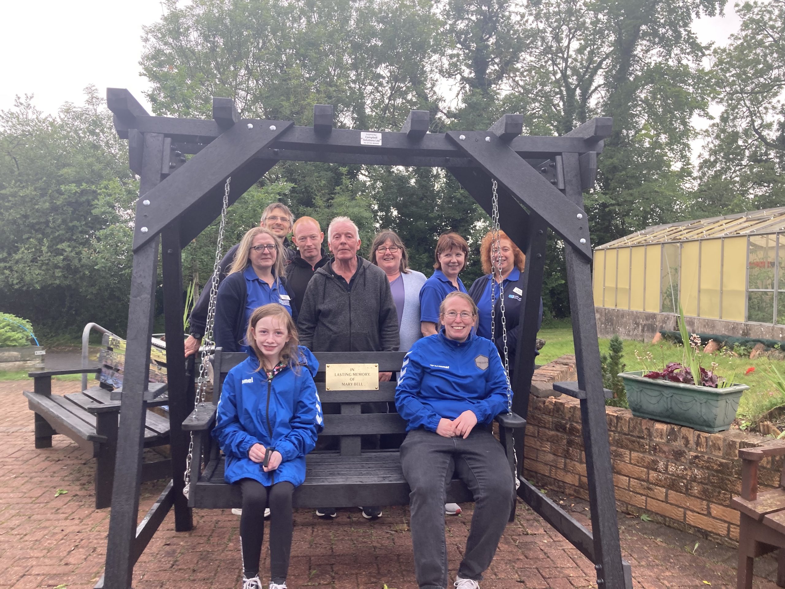Service Users and family and friends of the late Mary Bell presenting garden chair swing to Drumcoo Day Centre/ Day Opportunities