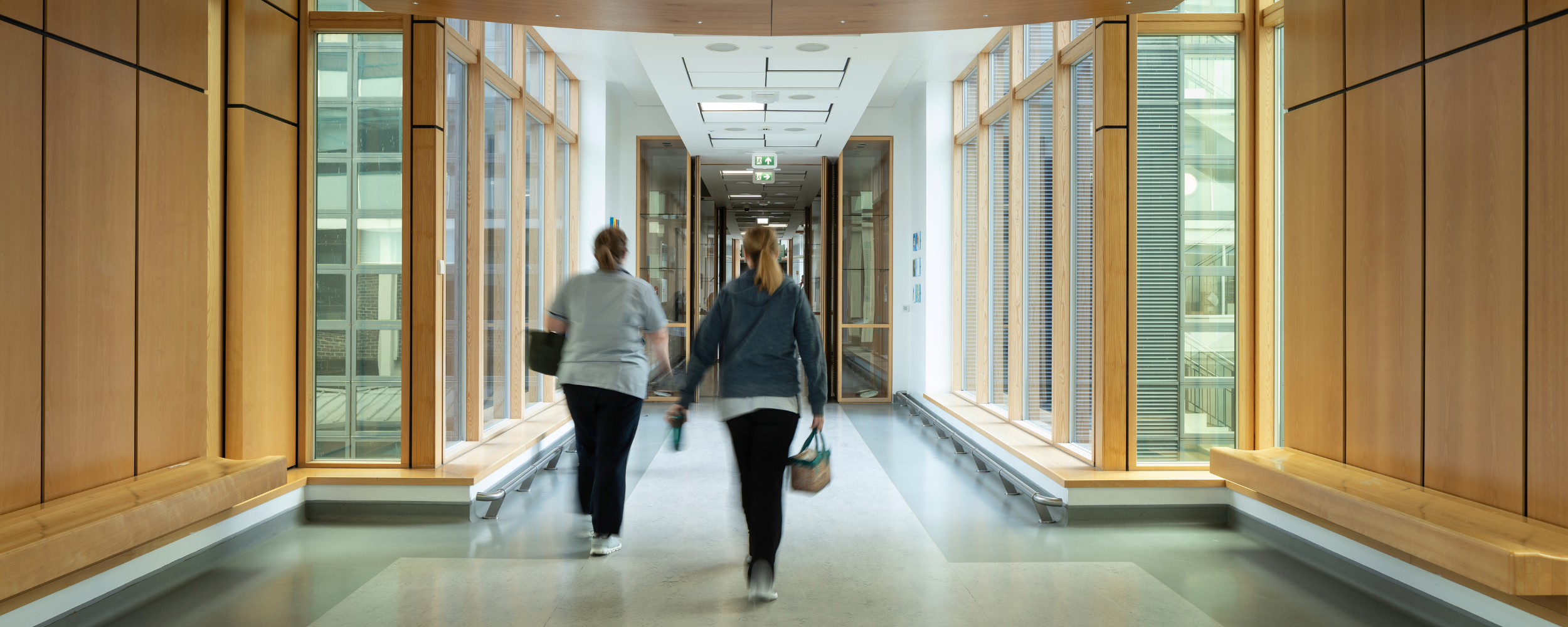 Two people walking along hospital corridor