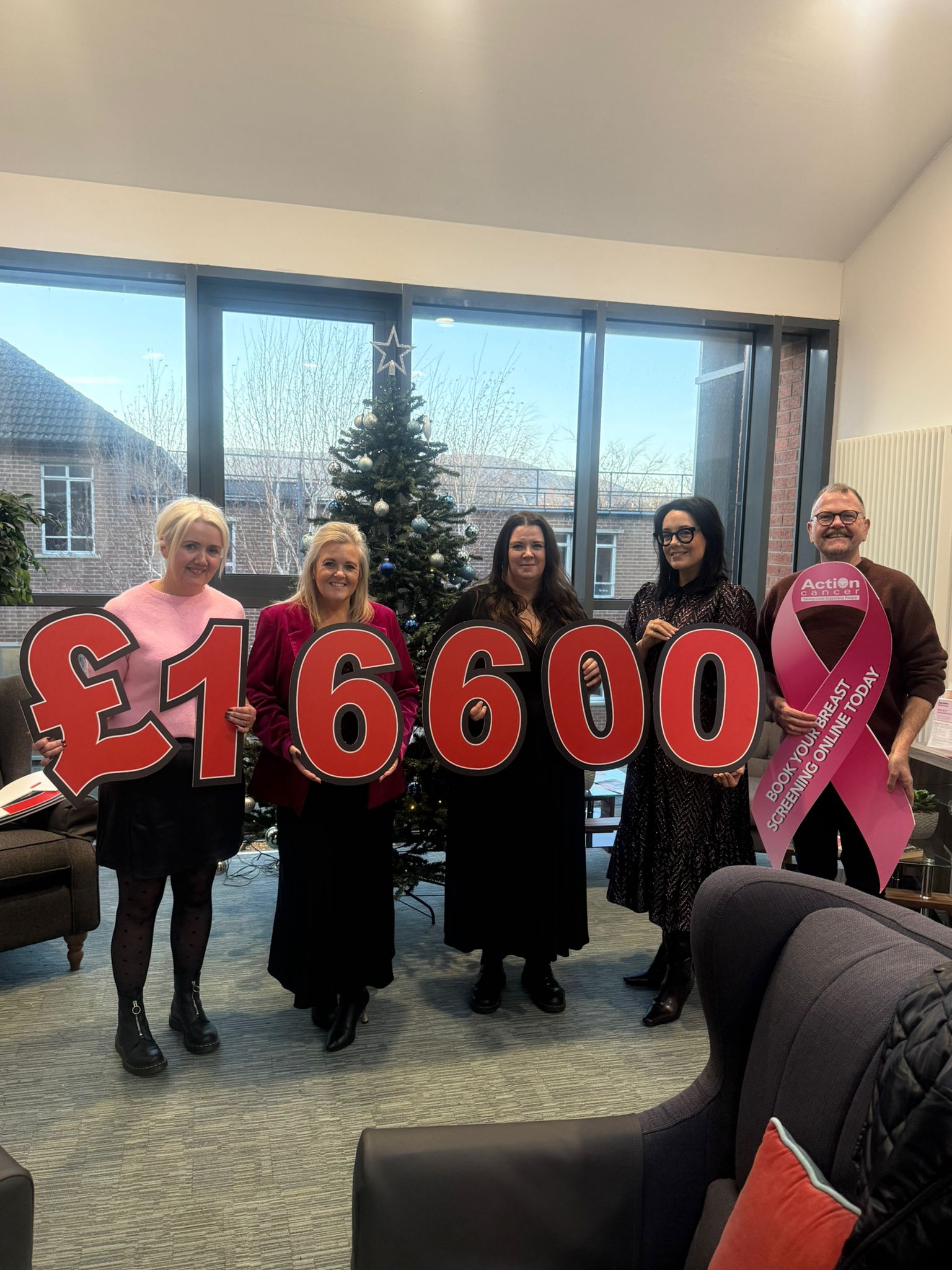 Staff with numbers donating £16600 to a breast cancer charity