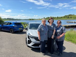 staff members standing in front of a car