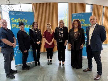 Staff pictured at the launch of safety planning video - with two pop up banners in background in foyer setting