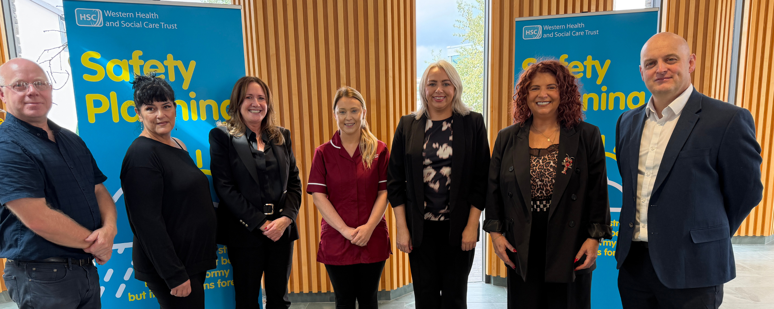 Staff pictured at the launch of the safety planning video with 2 pop up banners in foyer setting
