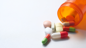 a picture showing different medication pills spilling out of a a small container