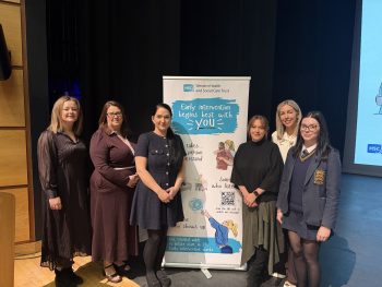 Group of people standing in front of pull up banner promoting Early Intervention Animation Launch