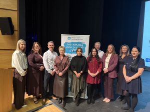 Large group of people standing in front of pull up banner promoting Early Intervention Animation Launch